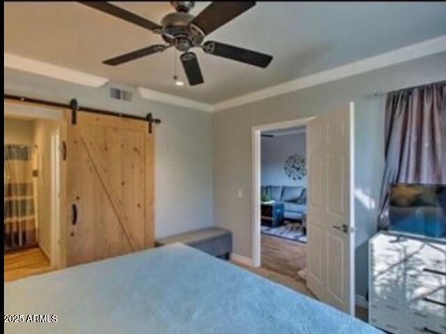 9450 E Becker Ln Unit 2099, Scottsdale, AZ 85260 - bedroom featuring a barn door, ornamental molding, and a ceiling fan