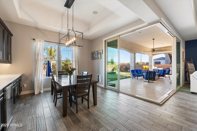 dining area with a tray ceiling, ceiling fan with notable chandelier, and a wealth of natural light