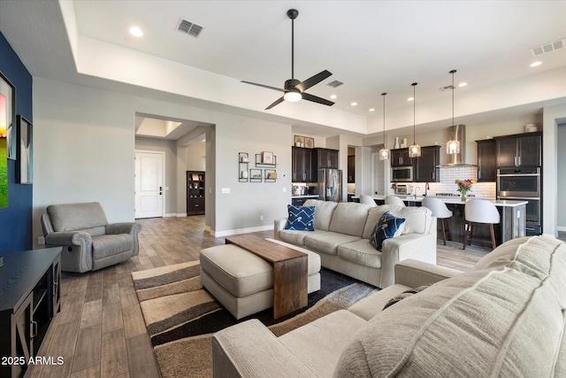 living room featuring a raised ceiling, dark hardwood / wood-style floors, and ceiling fan