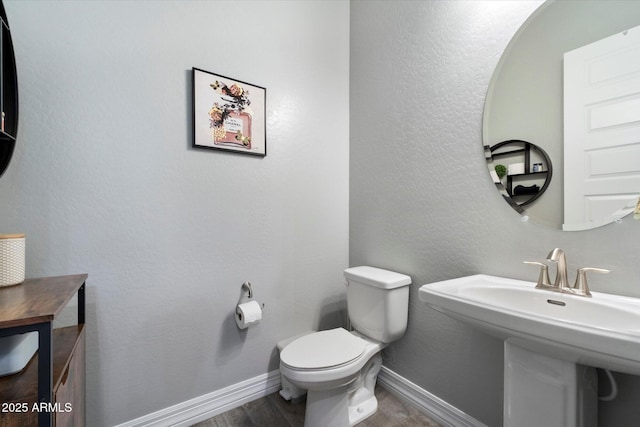 bathroom featuring wood-type flooring, toilet, and sink