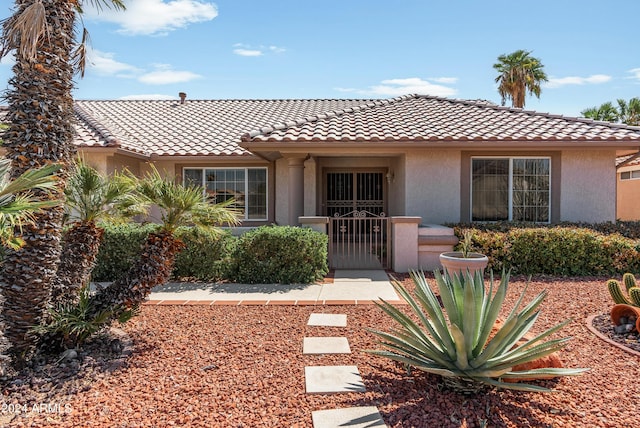 view of front of home with a gate, a tiled roof, and stucco siding