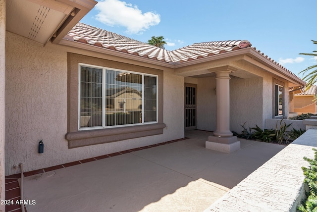 view of side of property featuring a patio, a tiled roof, and stucco siding