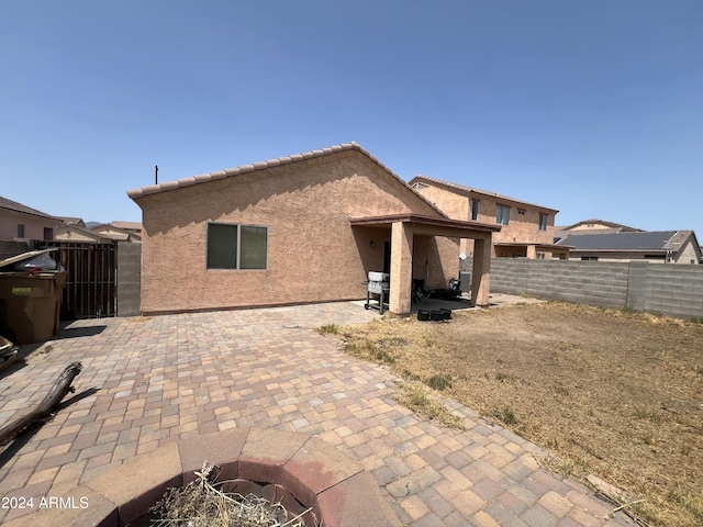 rear view of property with a fenced backyard, stucco siding, a tile roof, and a patio