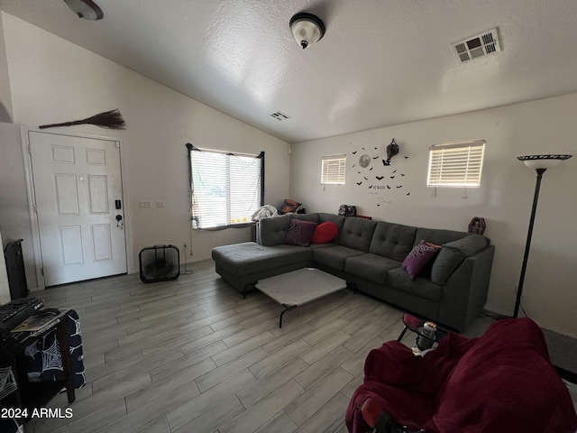 living area featuring visible vents, a textured ceiling, wood finished floors, and vaulted ceiling