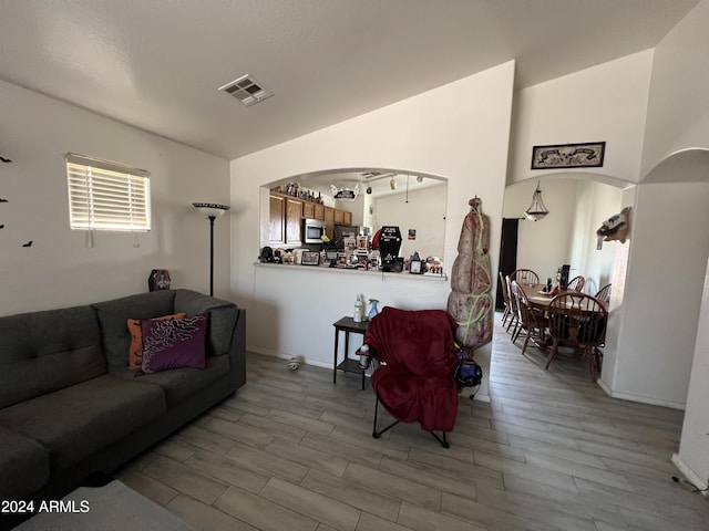 living room featuring wood finished floors, visible vents, and arched walkways
