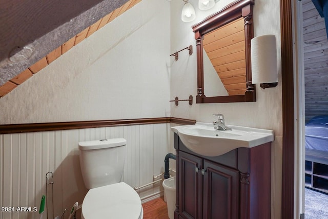 bathroom with toilet, vanity, and lofted ceiling