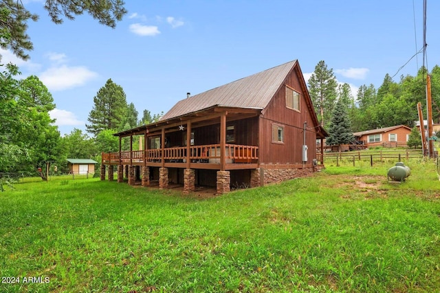 rear view of house featuring a lawn, metal roof, and fence