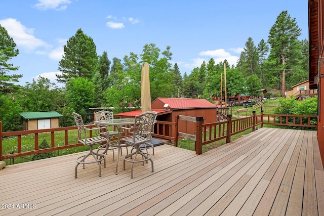 wooden deck with an outbuilding, outdoor dining space, and a shed