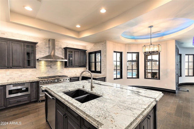 7254 E Sonoran Trl, Scottsdale, AZ 85266 - kitchen with wall chimney range hood, a tray ceiling, dark wood-style flooring, glass insert cabinets, and recessed lighting
