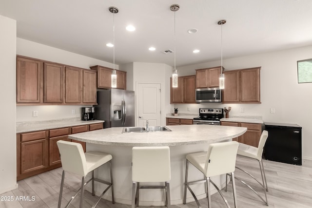 27418 W Mohawk Ln, Buckeye, AZ 85396 - kitchen with appliances with stainless steel finishes, a sink, recessed lighting, brown cabinetry, and a kitchen breakfast bar
