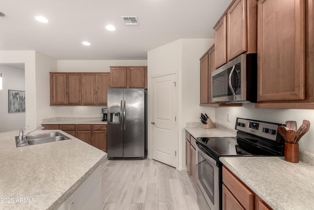 27418 W Mohawk Ln, Buckeye, AZ 85396 - kitchen featuring stainless steel appliances, a sink, brown cabinetry, light countertops, and recessed lighting