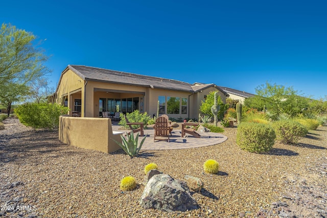 rear view of property with a patio and a fire pit