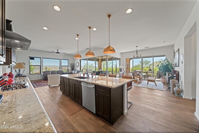 kitchen with sink, stainless steel appliances, light stone counters, pendant lighting, and ceiling fan with notable chandelier