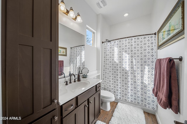 bathroom featuring wood-type flooring, vanity, toilet, and walk in shower