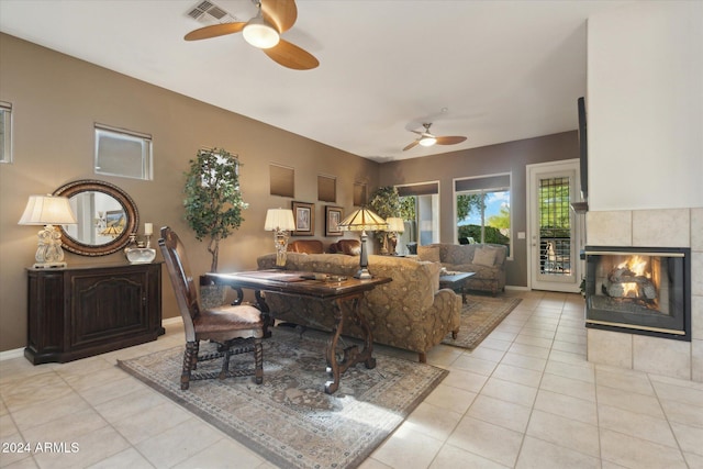 dining area featuring ceiling fan, a fireplace, and light tile patterned flooring