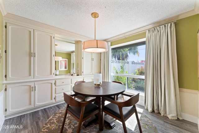 dining room featuring a textured ceiling, dark wood-type flooring, baseboards, and ornamental molding