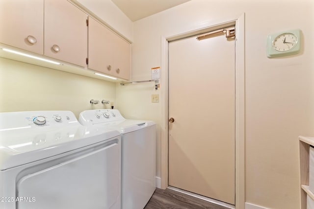 clothes washing area featuring washing machine and clothes dryer, cabinet space, and dark wood-type flooring