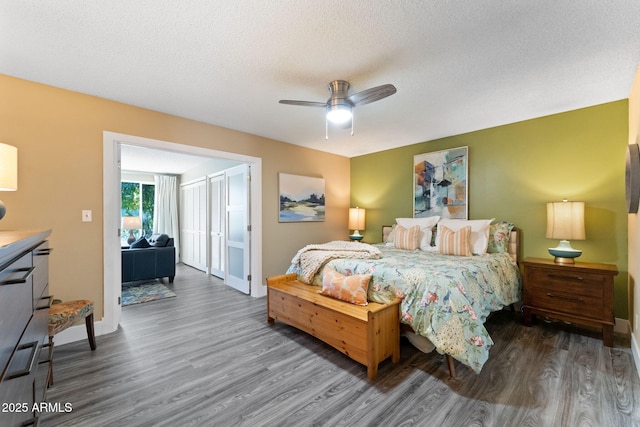 bedroom with a ceiling fan, wood finished floors, baseboards, and a textured ceiling