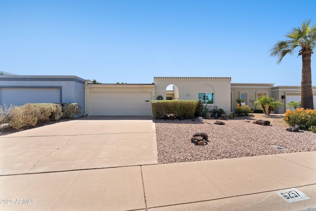 view of front facade with concrete driveway, an attached garage, and stucco siding