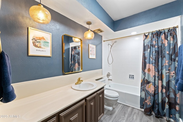 bathroom featuring vanity, wood finished floors, visible vents, shower / tub combo, and toilet