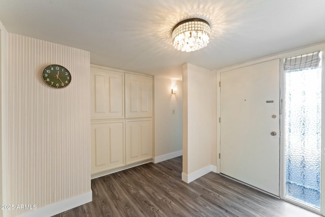 foyer featuring a notable chandelier, baseboards, and dark wood-style flooring