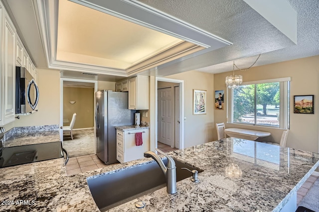 kitchen with a chandelier, stainless steel appliances, a raised ceiling, and sink