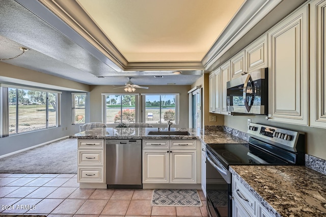 kitchen featuring light carpet, dark stone counters, sink, a textured ceiling, and stainless steel appliances