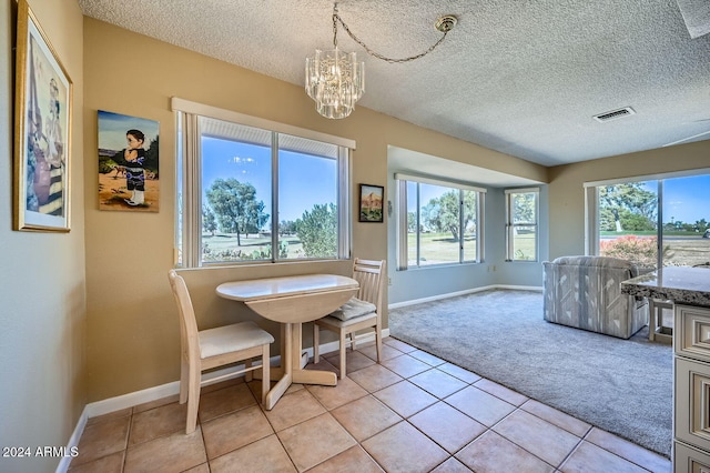 tiled dining room featuring a healthy amount of sunlight, a textured ceiling, and an inviting chandelier