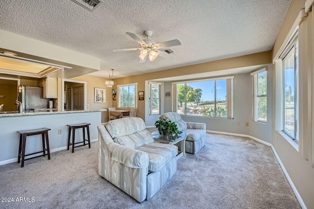 living room featuring ceiling fan, light colored carpet, and a textured ceiling