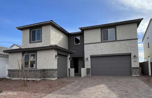 view of front of house with a garage, stone siding, decorative driveway, and stucco siding