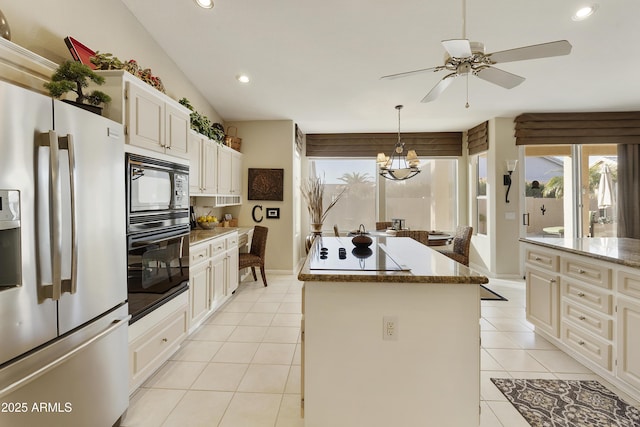 kitchen featuring decorative light fixtures, light tile patterned floors, light stone countertops, a kitchen island, and black appliances