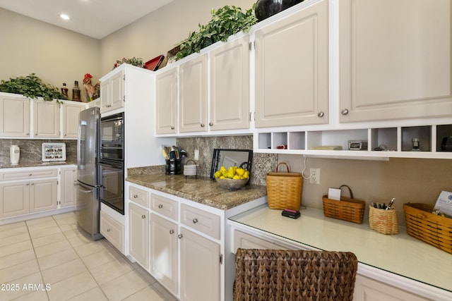 kitchen with light tile patterned floors, white cabinetry, black appliances, and stone counters