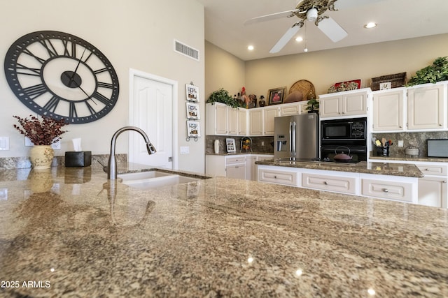 kitchen featuring white cabinets, black appliances, decorative backsplash, and sink