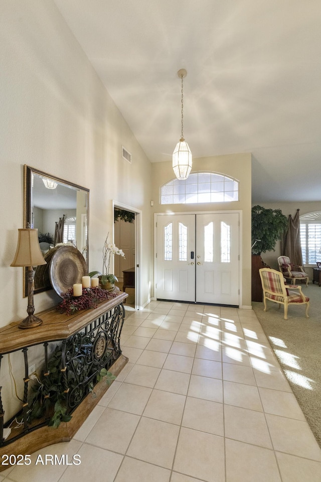 foyer featuring high vaulted ceiling and light tile patterned flooring