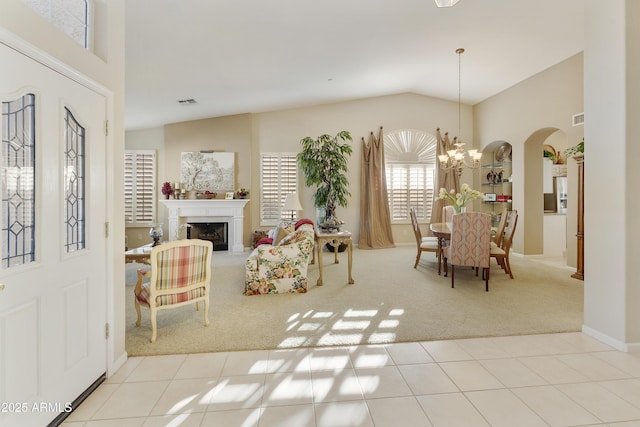 foyer entrance with light colored carpet, an inviting chandelier, and vaulted ceiling