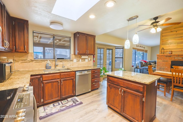 kitchen featuring sink, light wood-type flooring, hanging light fixtures, and stainless steel appliances