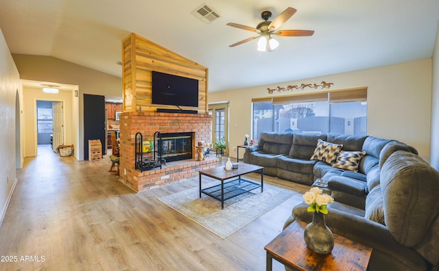 living room featuring light hardwood / wood-style floors, lofted ceiling, ceiling fan, and a fireplace