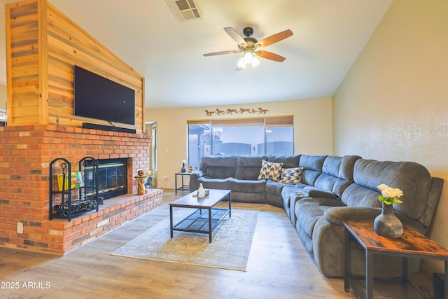 living room featuring vaulted ceiling, a brick fireplace, ceiling fan, and wood-type flooring