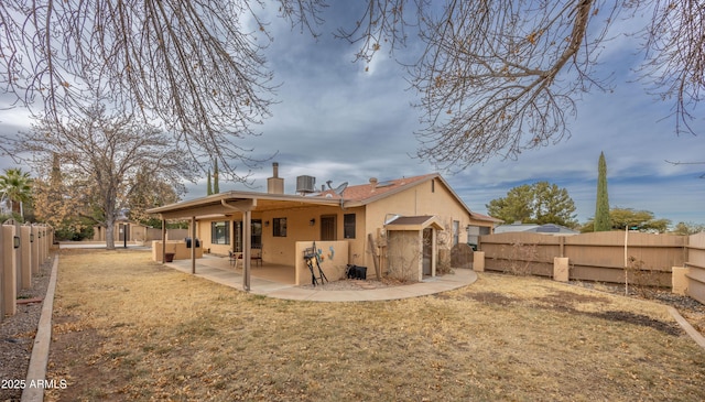 rear view of house featuring central air condition unit, a patio area, and a lawn