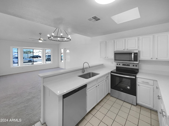 kitchen featuring white cabinets, sink, a skylight, light colored carpet, and stainless steel appliances