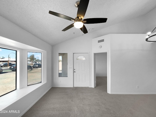 entryway with carpet flooring, a textured ceiling, ceiling fan with notable chandelier, and vaulted ceiling