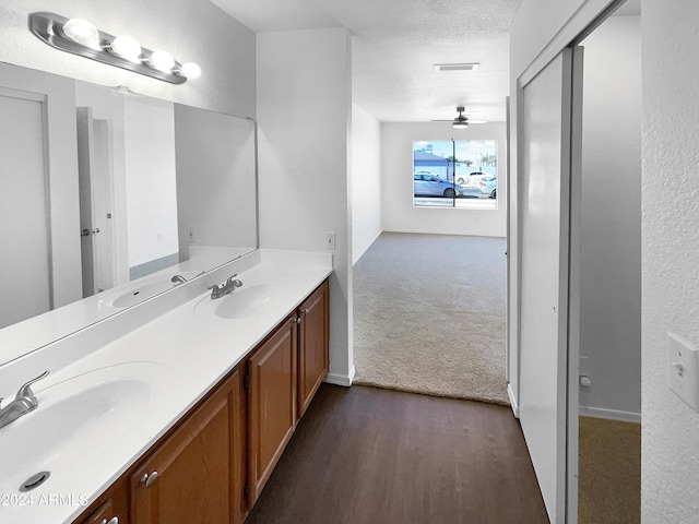 bathroom with ceiling fan, wood-type flooring, a textured ceiling, and vanity