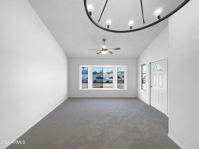 unfurnished living room with lofted ceiling, ceiling fan, carpet flooring, and a textured ceiling