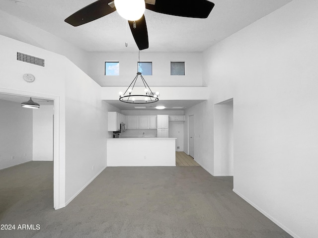 unfurnished living room with light carpet and ceiling fan with notable chandelier