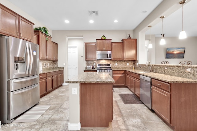 kitchen featuring kitchen peninsula, light stone countertops, stainless steel appliances, sink, and decorative light fixtures