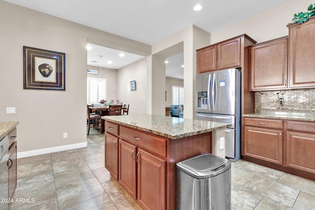 kitchen with decorative backsplash, stainless steel appliances, light stone counters, and a kitchen island