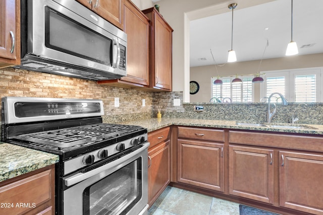 kitchen with light stone countertops, sink, stainless steel appliances, and plenty of natural light