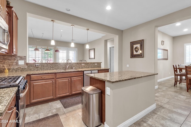 kitchen featuring a wealth of natural light, sink, stainless steel appliances, decorative light fixtures, and decorative backsplash