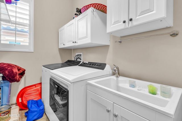 clothes washing area featuring washer and clothes dryer, cabinets, and sink