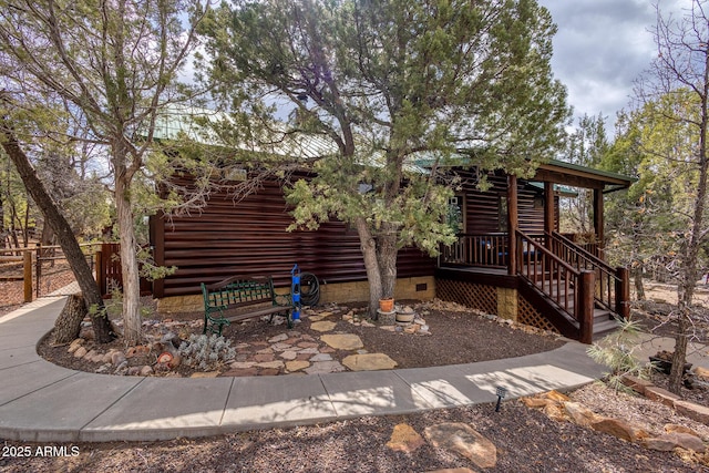 view of front of home with crawl space and fence